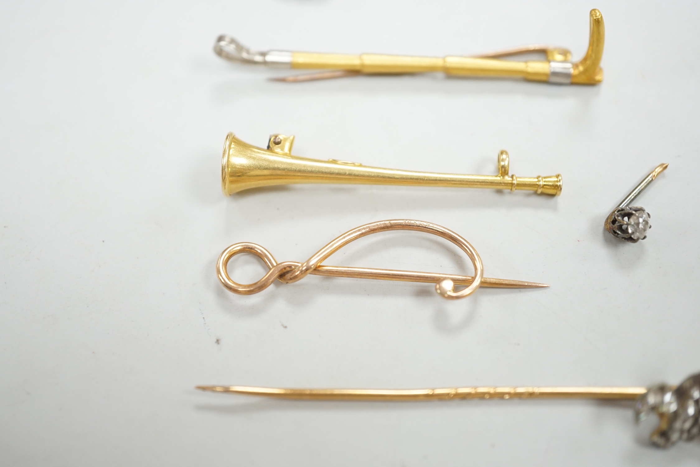 An Edwardian 15ct riding crop brooch(a.f.), 59mm, 2.8 grams, an 18ct hunting horn brooch (lacking pin) 2.1 grams, two Victorian diamond cluster set stick pins including swan in flight, a diamond set pin terminal, gross 4